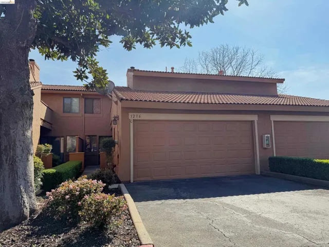 Mediterranean / spanish house with asphalt driveway, stucco siding, an attached garage, and a tiled roof