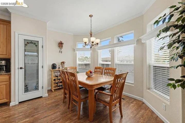 Dining room featuring ornamental molding, dark wood-type flooring, and suspended lighting