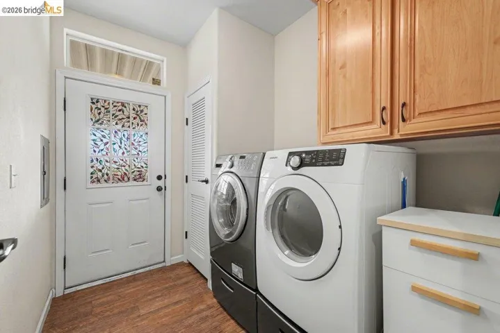 Laundry room with dark wood-type flooring, washing machine and dryer, and cabinet space