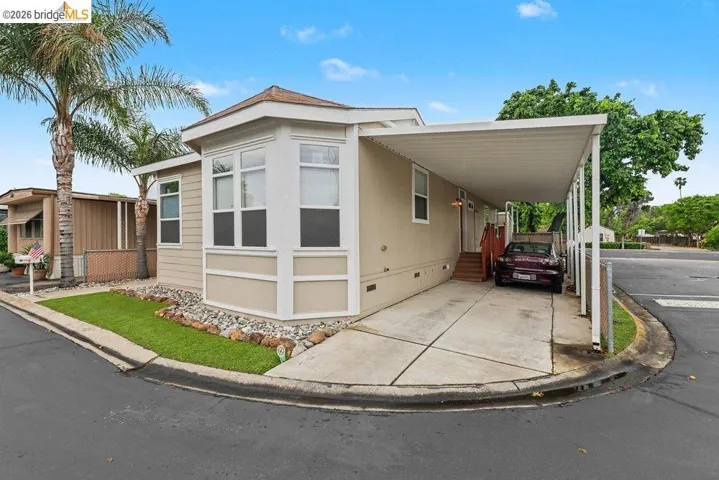 View of front facade with crawl space, an attached carport, concrete driveway, and a porch