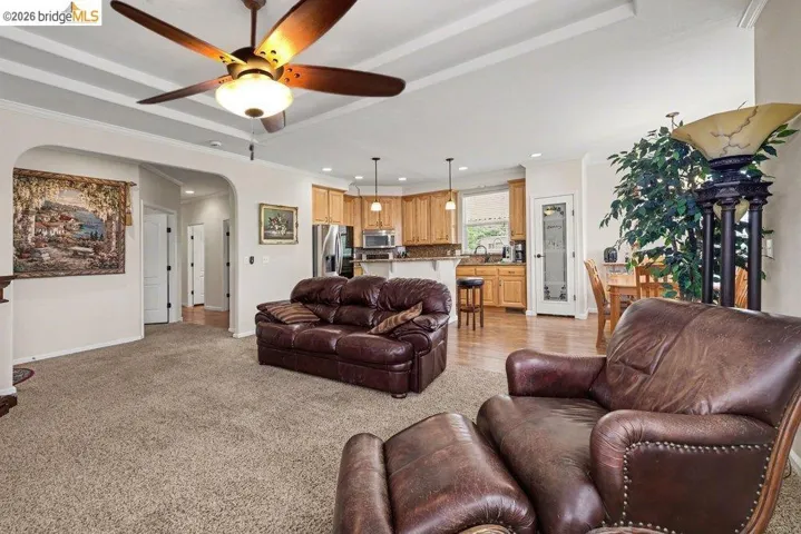 Living room featuring arched walkways, ceiling fan, ornamental molding, recessed lighting, and light colored carpet