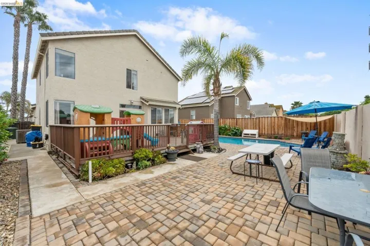 Rear view of house featuring outdoor dining space, a fenced backyard, a patio, stucco siding, and a deck