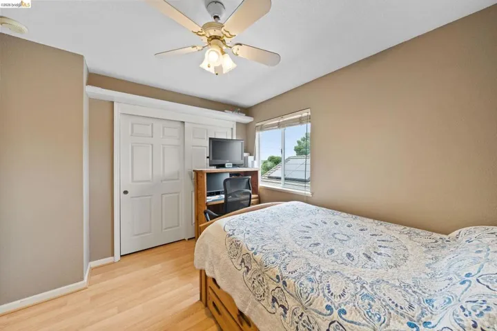 Bedroom with light wood-type flooring, a ceiling fan, and a closet