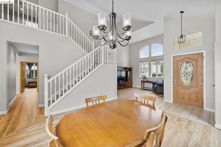 Dining space with a high ceiling, light wood-style flooring, and hanging lights