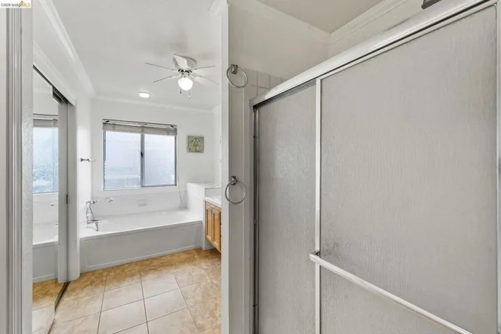 Full bath featuring vanity, a shower stall, ornamental molding, a bath, and a ceiling fan