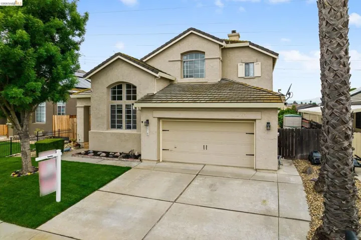 Traditional home with a chimney, stucco siding, driveway, a garage, and a tile roof