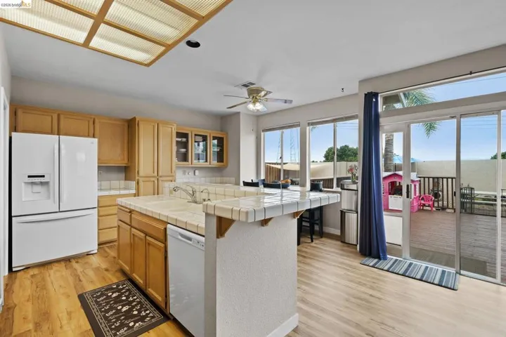 Kitchen featuring tile countertops, a kitchen island, white appliances, light wood-style floors, and ceiling fan