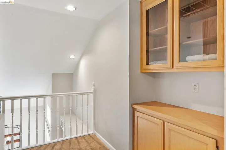 Corridor featuring light carpet, lofted ceiling, recessed lighting, and a textured wall