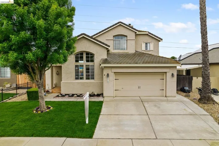 Traditional home featuring stucco siding, driveway, and a tiled roof