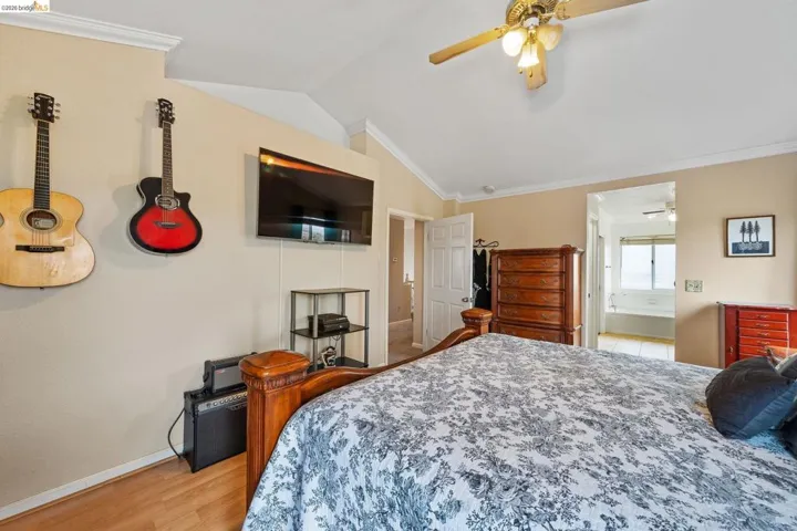 Bedroom with ornamental molding, lofted ceiling, ceiling fan, and light wood-style flooring