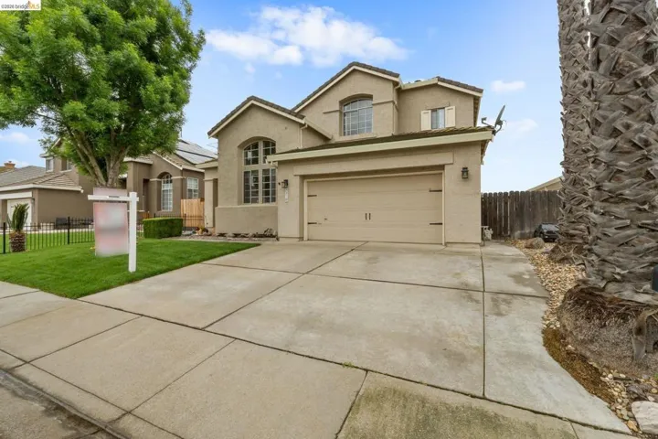 Traditional-style home featuring concrete driveway and stucco siding