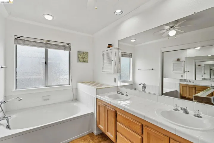 Bathroom featuring a bath, ceiling fan, double vanity, ornamental molding, and recessed lighting