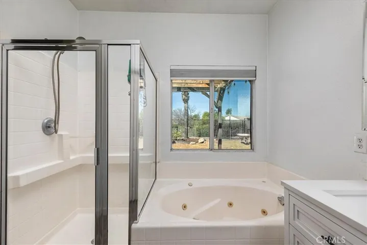 Primary bath with jetted tub, separate shower and view to back yard.
