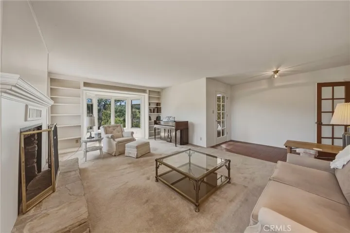 Formal living room with fireplace, large windows and plenty of book shelves.