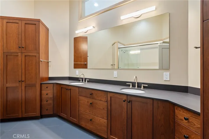 This full main bath is spacious! It has 2 sinks, paper stone countertop, and ample hardwood cabinetry.
