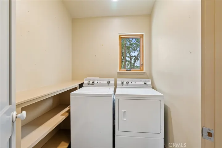 Indoor laundry has built-in shelves and window with quick access to the back door.