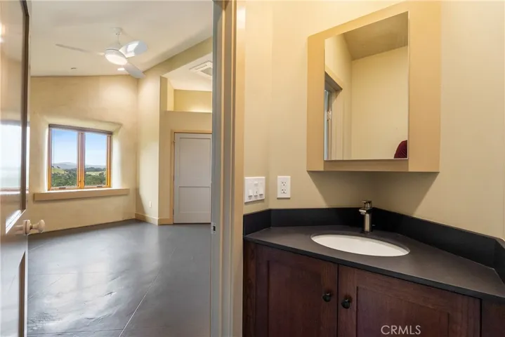 The ensuite half-bath has a single sink, paper stone counter, and hard wood cabinet.