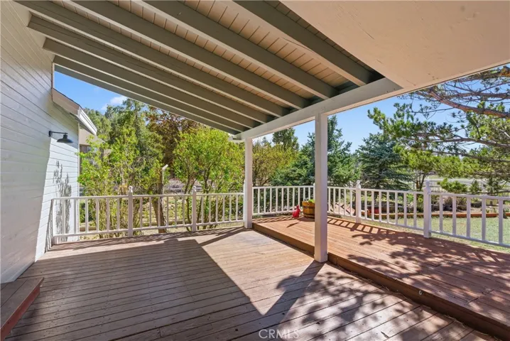 Side covered deck looks out to beautiful trees and greenery
