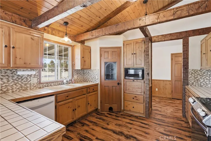 Nice sized kitchen has cute walk-in pantry, built in cabinet area with microwave, dishwasher, nice light fixtures, wood cabinets with attractive hardware.