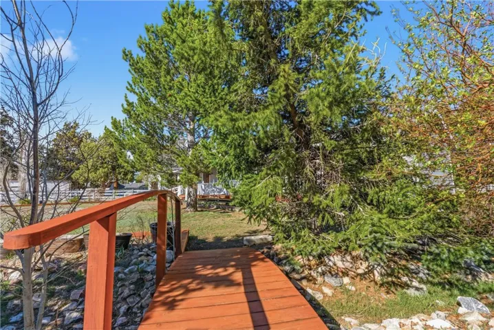 Backyard walking bridge over dry stream with view of home through trees.