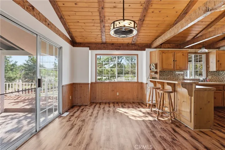 Dining area and breakfast bar with decorative ceiling fan light fixture, attractive wainscoting, with slider opens to side deck to take in all the views.