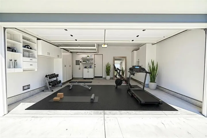 Garage with lots of storage and work area. Virtually staged as gym