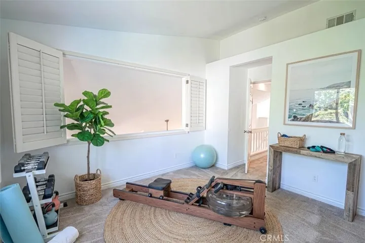 Upstairs guest bedroom with wood shutters and view of Living Room. Virtually staged as home gym.