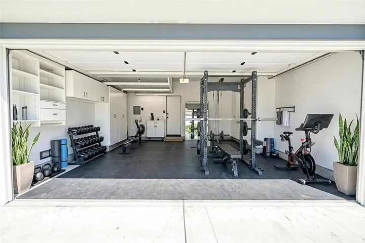 Garage with lots of storage and work area. Virtually staged as gym
