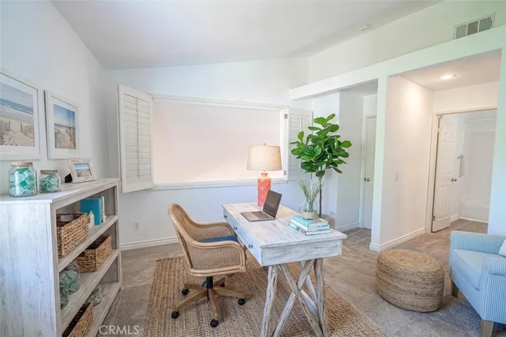 Upstairs guest bedroom with wood shutters and view of Living Room. Virtually staged as home office.