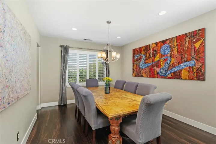 Formal dining with Luxury Vinyl Plank flooring, designer chandelier, plantation shutters and draperies