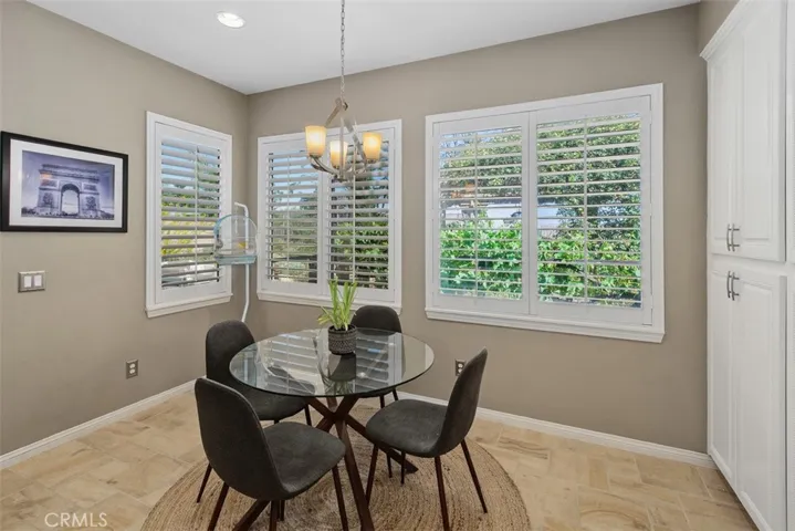 Spacious dining area with designer chandelier and plantation shutters