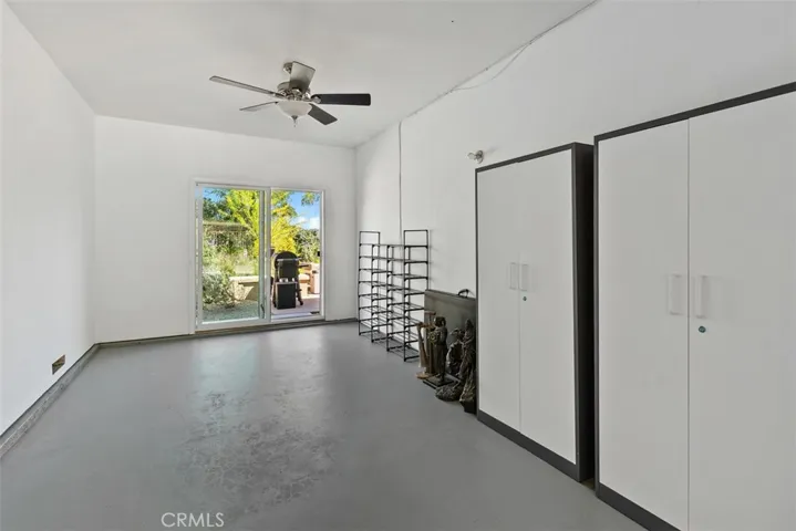 Third-car tandem space thoughtfully converted into a studio complete with ceiling fan and sliding doors that open to the backyard. This versatile area can easily be restored to a three-car tandem garage or repurposed as an ADU, gym or office