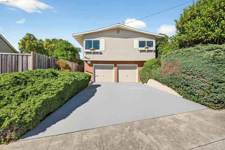 View of front facade with brick siding, driveway, and an attached garage