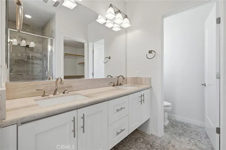 Primary bathroom with dual sinks, large walk in shower and walk in closet