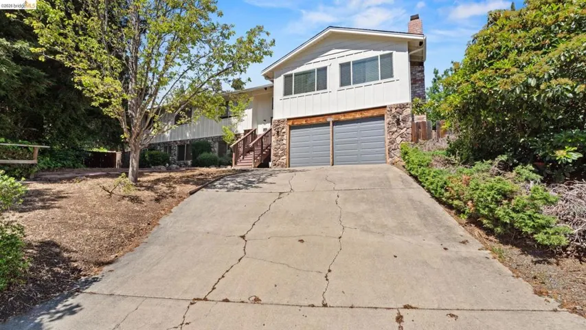 View of front of house featuring stone siding, driveway, a garage, and a chimney