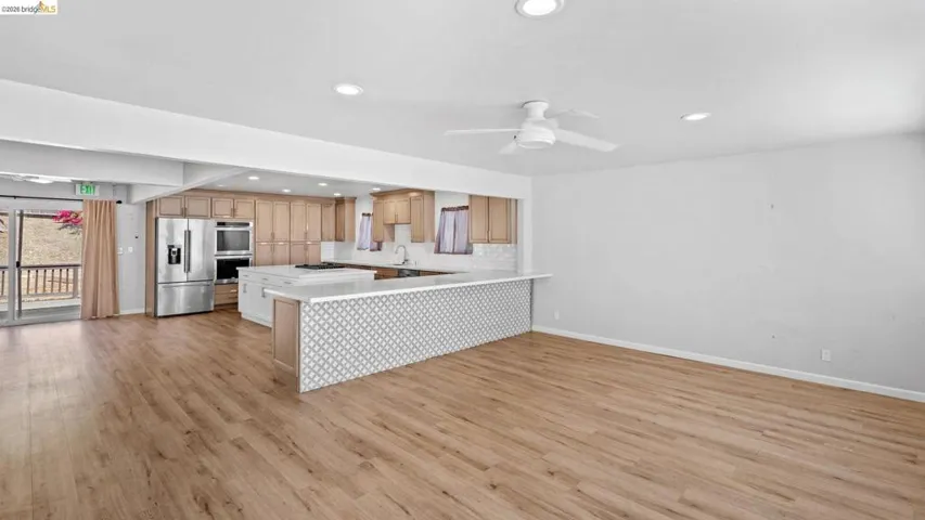Kitchen with a peninsula, light countertops, stainless steel appliances, a ceiling fan, and open floor plan