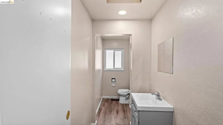 Bathroom featuring vanity, a textured wall, and light wood-style floors