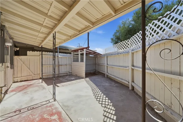 Covered and enclosed patio area w gate at the left leading to garage space.