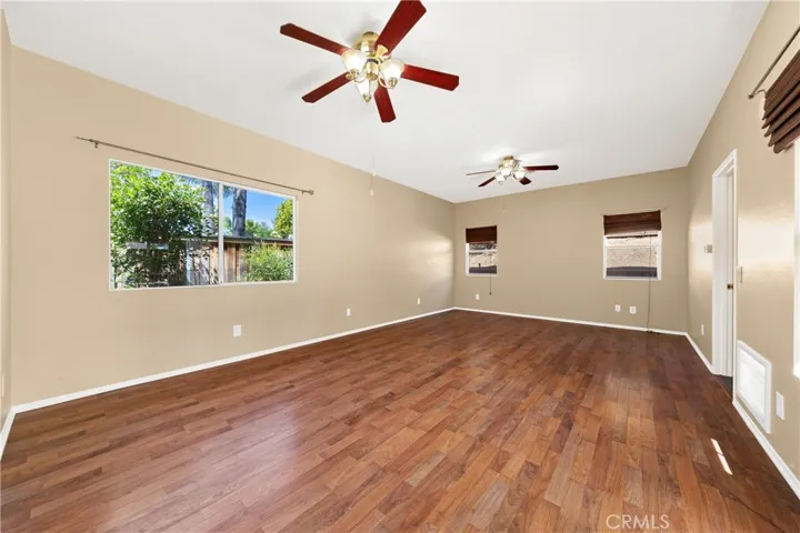 Spacious Downstairs Primary Bedroom With Ceiling Fan And Wood-Look Flooring