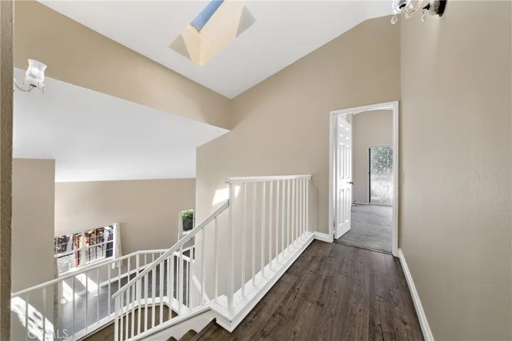 Open Staircase And Hallway With Vaulted Ceilings And Natural Light