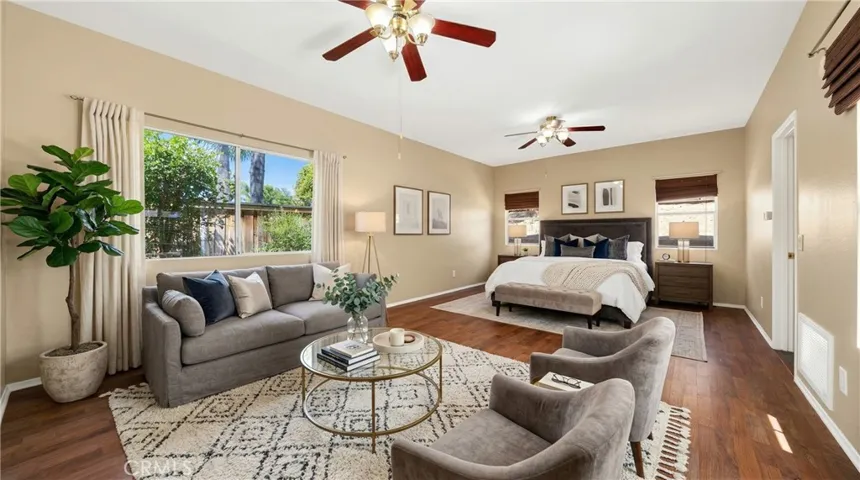 Spacious Downstairs Primary Bedroom With Ceiling Fan And Wood-Look Flooring - Digitally Staged