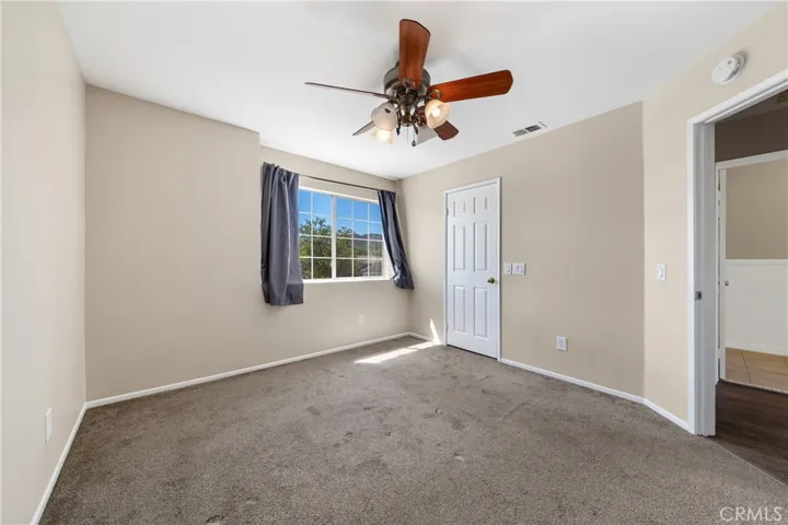 Upstairs Bedroom With Ceiling Fan, Natural Light, And Neutral Finishes