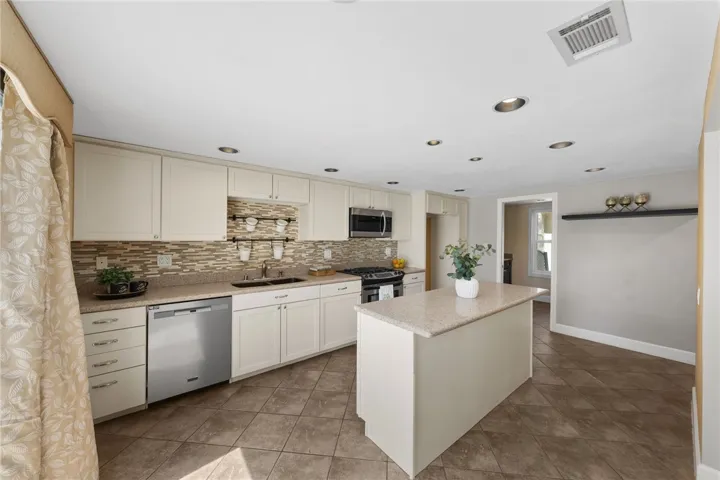 Functional kitchen layout includes generous counter space, a tile backsplash, and a central island suited for prep and casual seating.