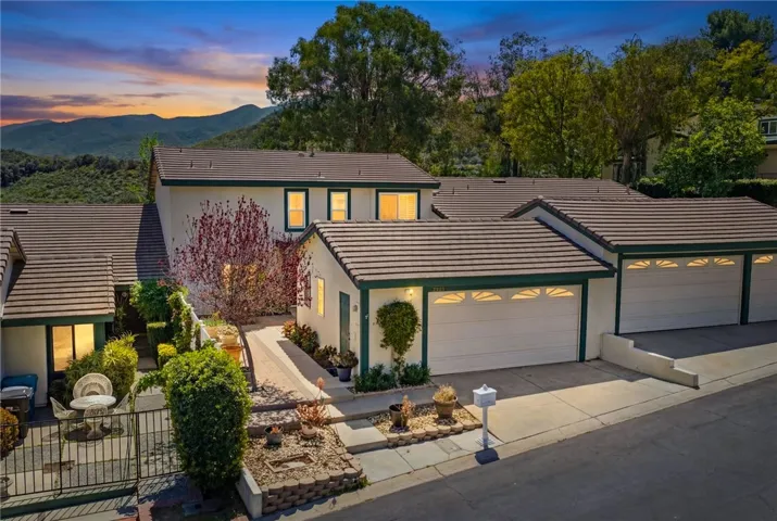 Home’s inviting curb appeal with a two-car garage, private entry walkway, and warm interior lighting.