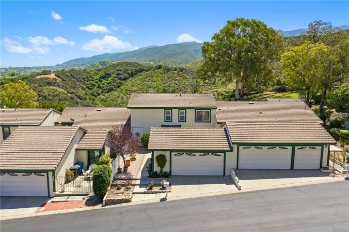 Elevated front view highlights the home’s placement within the community, framed by scenic hillside surroundings.
