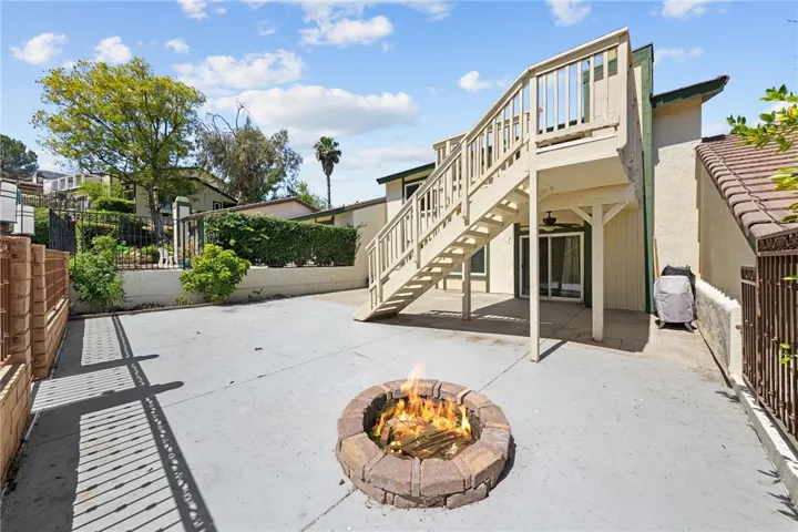 Expansive concrete patio with a built-in fire pit and direct access to the upper deck, creating a functional space for outdoor dining or relaxing.