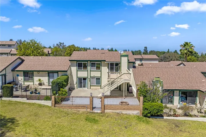 Aerial rear view emphasizes the fenced patio, upper deck, and direct connection to the expansive grassy area behind the home.