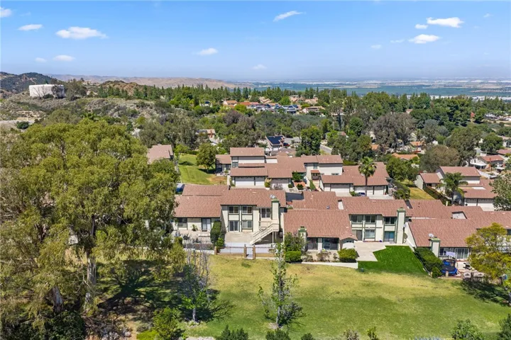 Rear aerial perspective captures the home’s position backing to open green space with neighboring hillside and valley views.