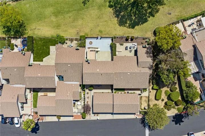 Overhead view showcasing the home’s position along a quiet residential street with a spacious rear patio and elevated backyard setting.