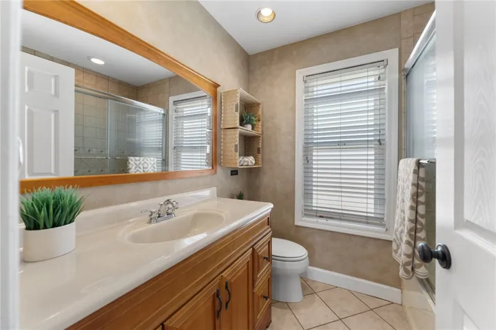 Full bathroom includes a large vanity, generous mirror, and a shower enclosure with window light.